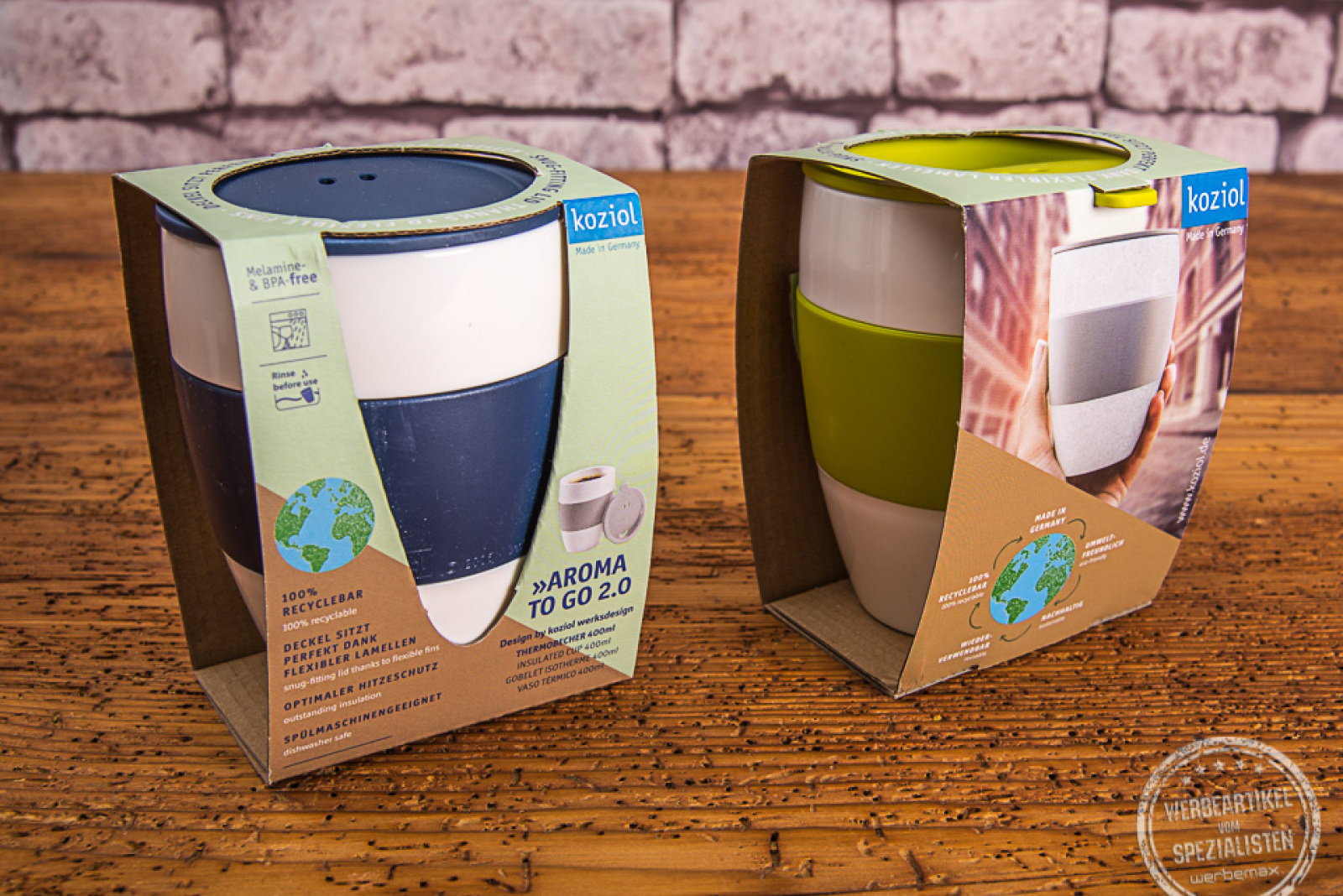 Zwei Kaffeebecher Aroma to go in Verpackung. Mit blauem Deckel und grünem Deckel. 