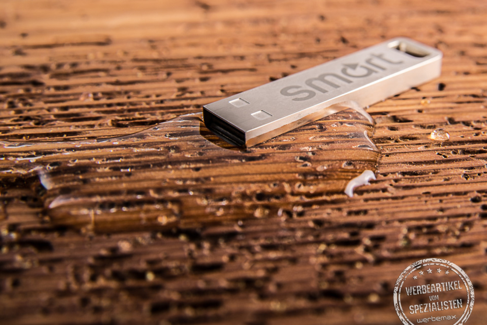 USB Stick Element auf Holzfläche liegend in silber aus Edelstahl als Werbeartikel.